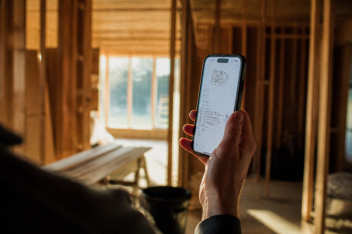 A hand holding a phone inside a house under construction.